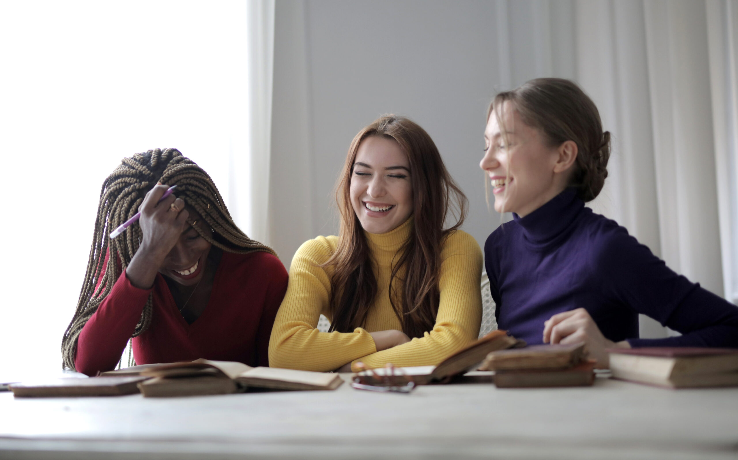 three young women sitting at table laughing
